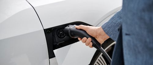 Closeup von Hand, die Stecker in E-Auto steckt
